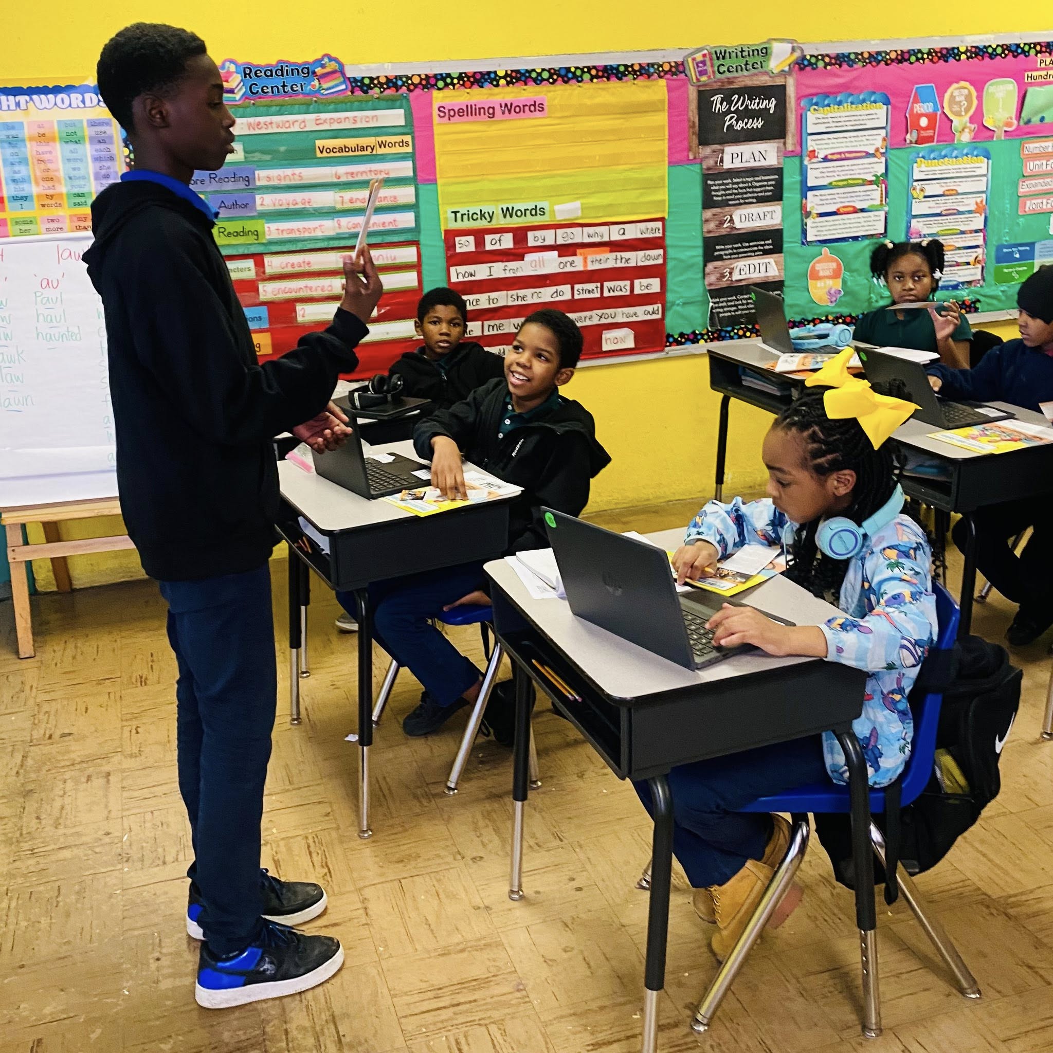 A teenage boy standing before a classroom of younger students.